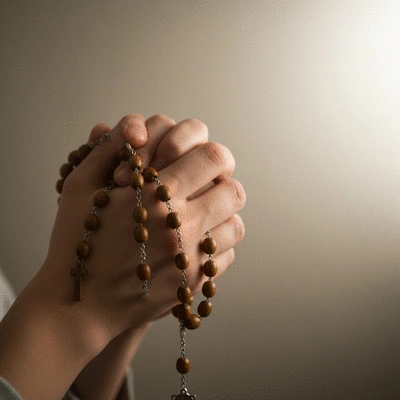 Person praying with rosary beads, soft light