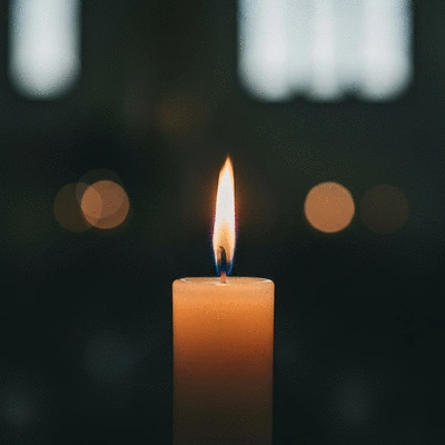 Zapalona świeca w kościele, symbolizująca pamięć o zmarłych