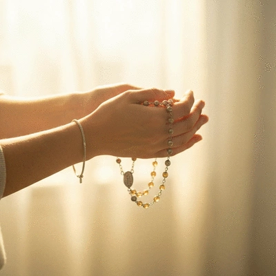 Ręce trzymające różaniec, z delikatnym światłem padającym na koraliki, symbolizujące modlitwę i spokój, no text, no words, no typography, clean image