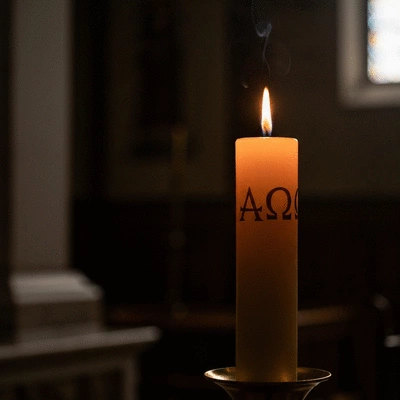 Świeca paschalna z symbolem Alfa i Omega, paląca się w ciemności kościoła