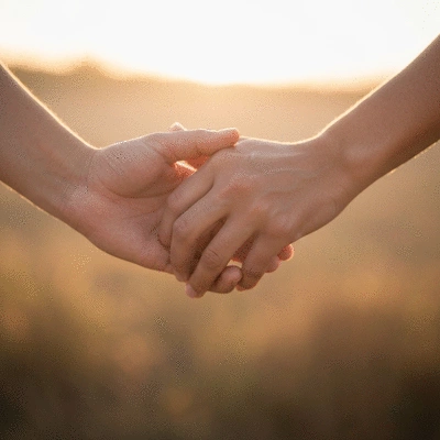 Symbolic image of two hands holding, representing love and connection, with a soft, warm background